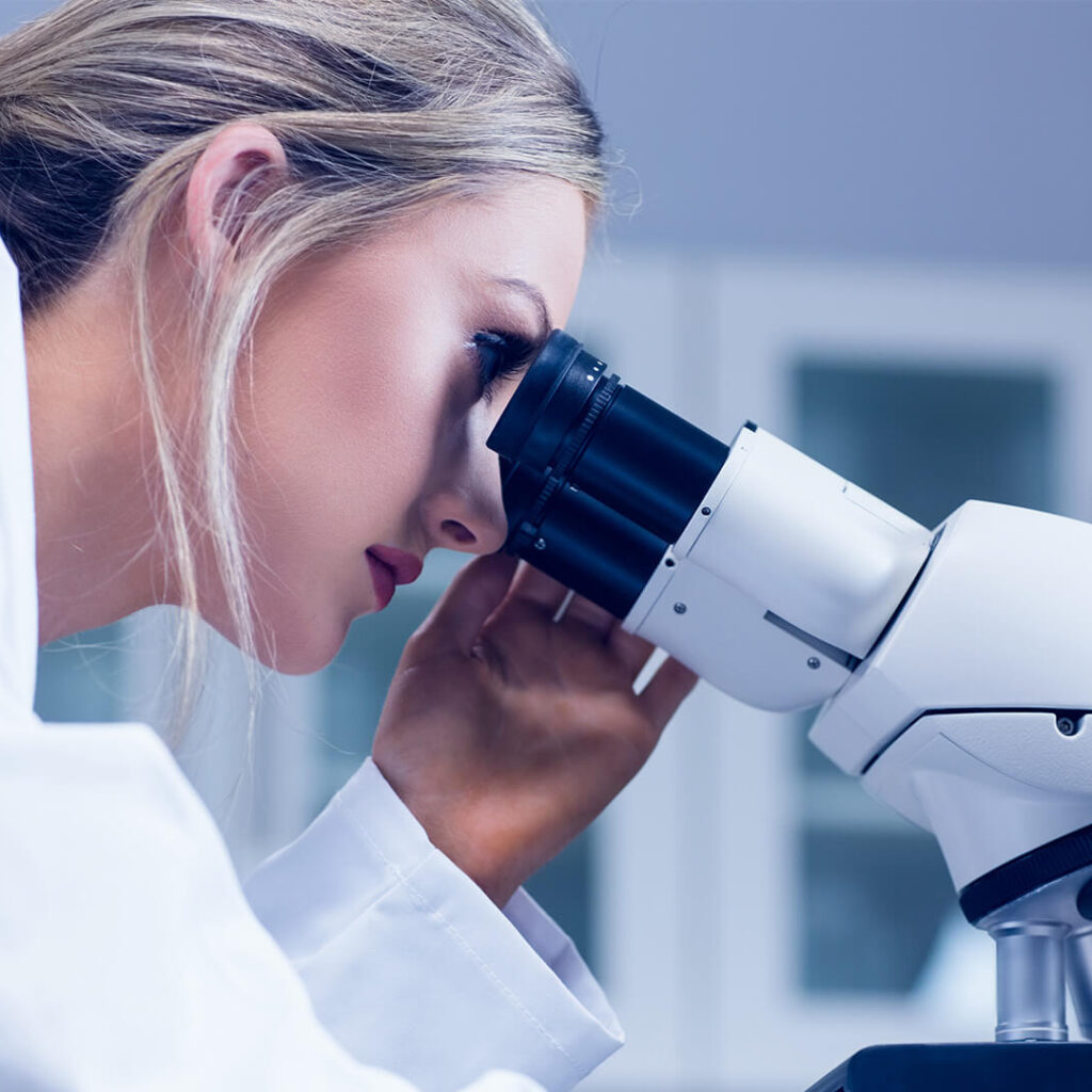 science student looking through a microscope in a lab