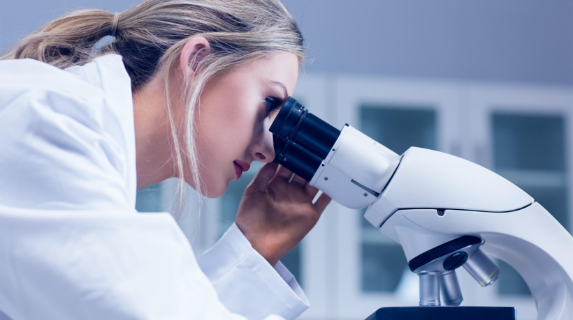 science student looking through a microscope in a lab