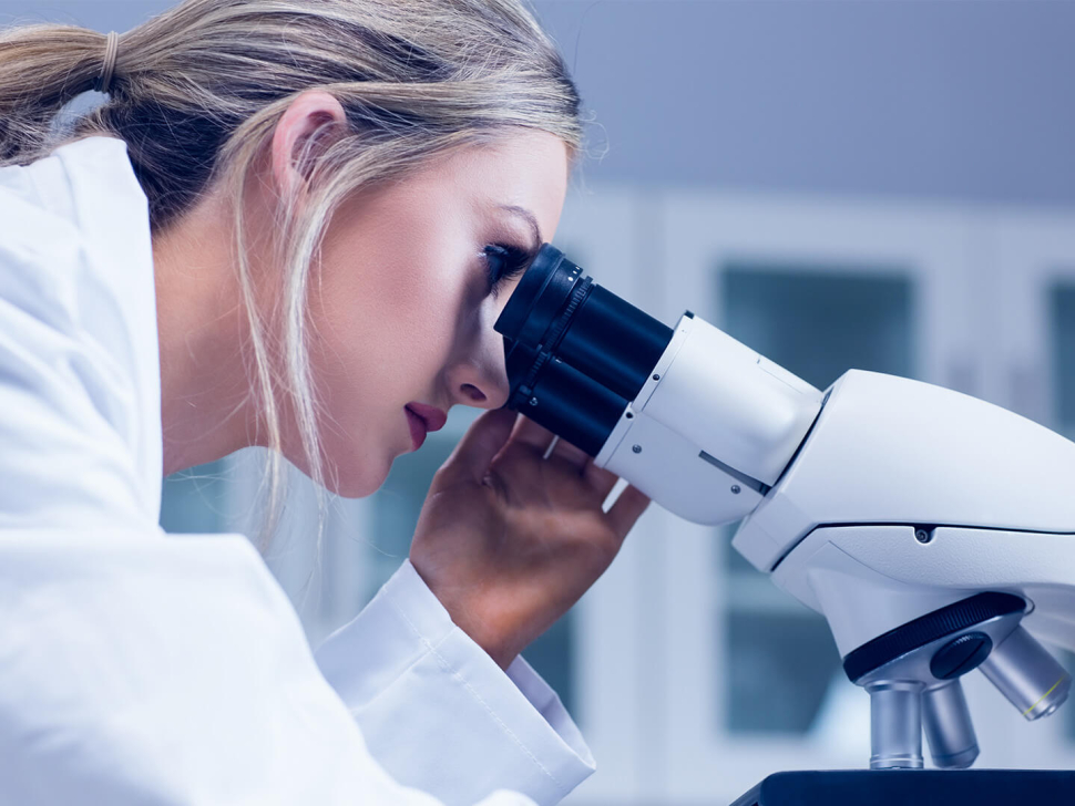 science student looking through a microscope in a lab