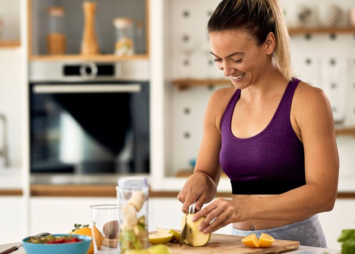 woman in fitness gear preparing a smoothie